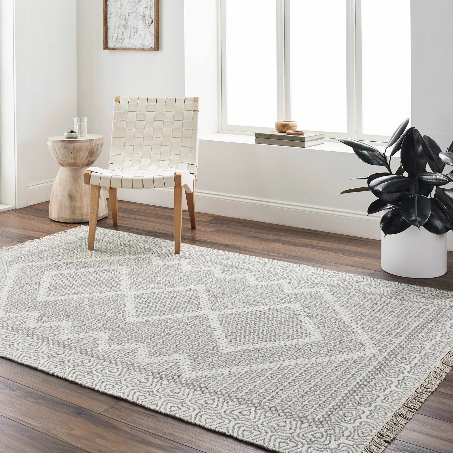 Living room scene with the Claus Area Rug in bone and cloud gray, woven chair, and wood side table. Roomscene-Rectangle