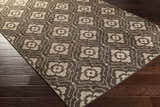 Close-up of the Claysville Area Rug, a beige and dark brown wool rug with a floral geometric pattern. Corner