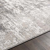 Close-up of the charcoal, gray, and light gray abstract design of the Calabasa Area Rug on dark wood flooring. Texture