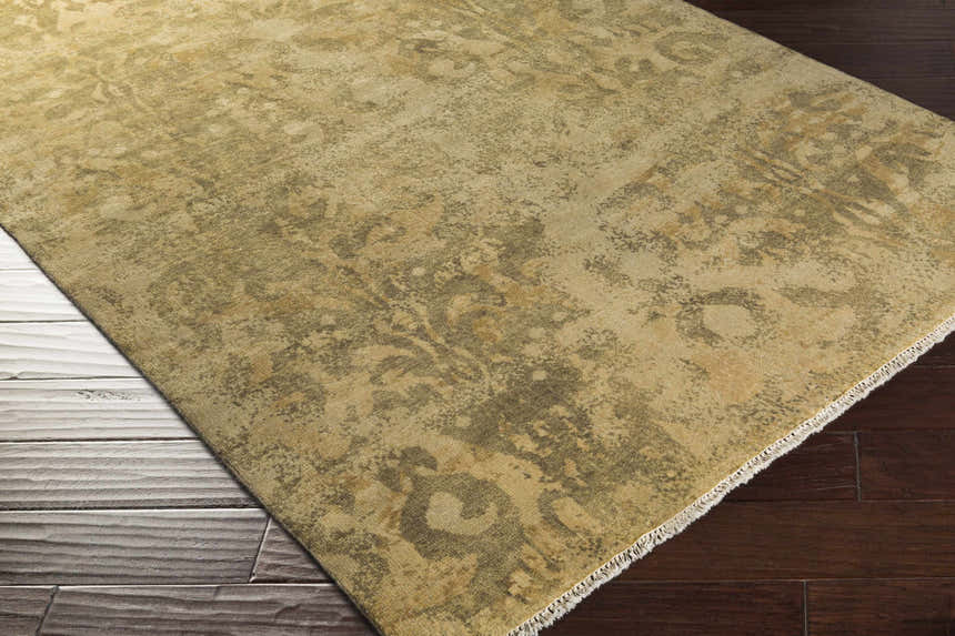 Close-up of the Cleburne Area Rug showing its light brown, olive, and tan colors and hand-knotted traditional design. Corner