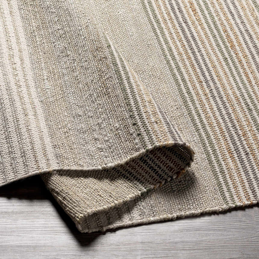 Close-up of the hand woven Calinog Area Rug. Features charcoal, green, beige, and tan stripes with a farmhouse texture. Fold