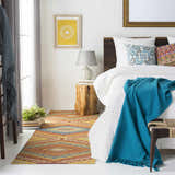 Bedroom scene with a Clutier Clearance Rug in beige, blue, and mustard colors adding warmth to the white floor. Roomscene-Rectangle
