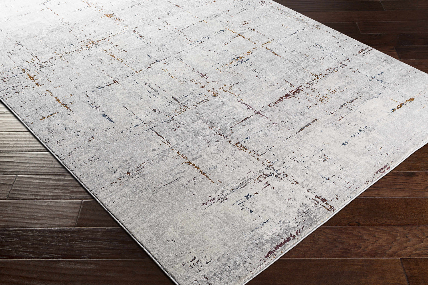 Close-up of a Concordia Faux Silk Rug. Abstract design in off-white, gray, burgundy, burnt orange, and navy on dark wood floors. Corner