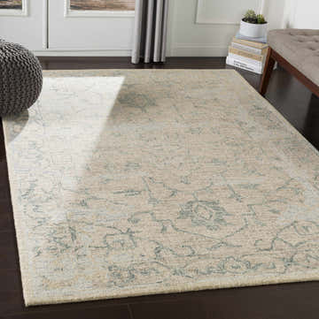 Living room scene with beige Connellsville area rug, gray pouf, and tufted bench on dark wood floor. Roomscene-Rectangle