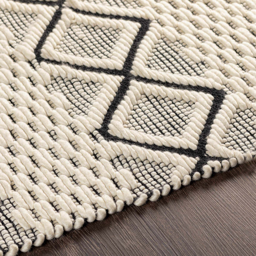 Close-up of the hand woven Cobourg Area Carpet. Black geometric pattern on cream 100% wool rug. Farmhouse style. Texture