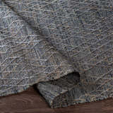 Close-up of the hand-woven Colinton Area Rug. Features a textured gray weave with a subtle geometric pattern. Fold