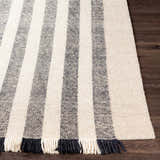 Close-up of a hand woven Contrecoeur Area Carpet. Black and cream wool stripes with fringe detail. Front