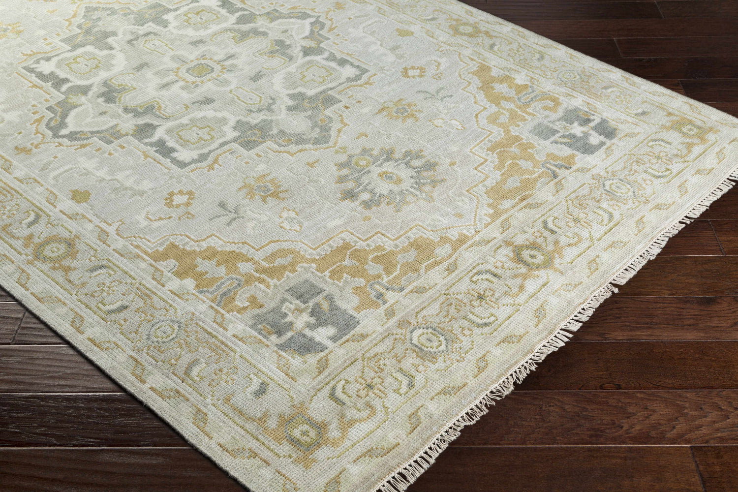 Close-up of the hand-knotted Convent Area Rug. Cream, light sage, mustard, and tan colors with a traditional oriental pattern. Corner