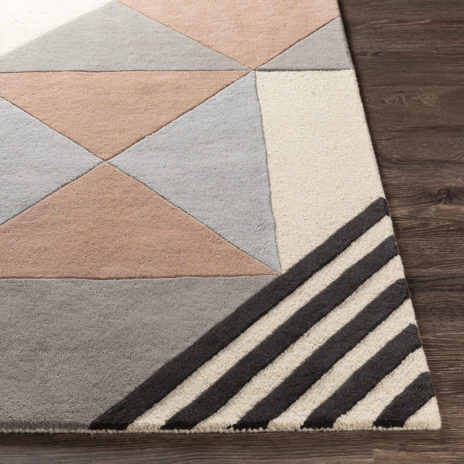 Close up of Coorparoo Wool Area Rug. Geometric design in beige, black, dusty pink, and gray on dark wood floor. Hand-tufted texture. Front