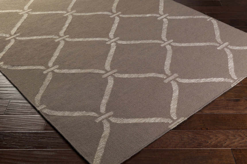 Close-up of the Coraopolis Area Carpet in light gray and taupe with a contemporary lattice design on dark wood floors. Corner