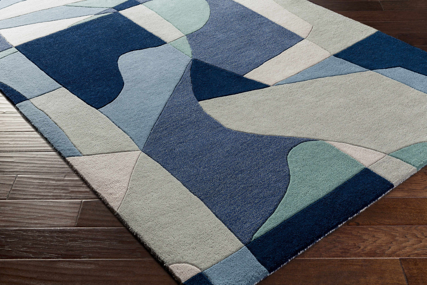 Close up of Crawfordsville rug showing the modern geometric pattern in dark blue, denim, dusty sage, and gray wool. Corner