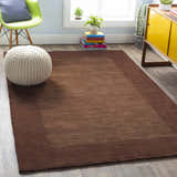 Living room scene with a Bordered Solid Brown Wool Rug, white pouf, green chair, and yellow cabinet. Roomscene-Rectangle