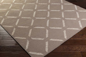 Close-up of the Cridersville Area Carpet. Light gray wool rug with a taupe geometric pattern on dark wood floors. Corner