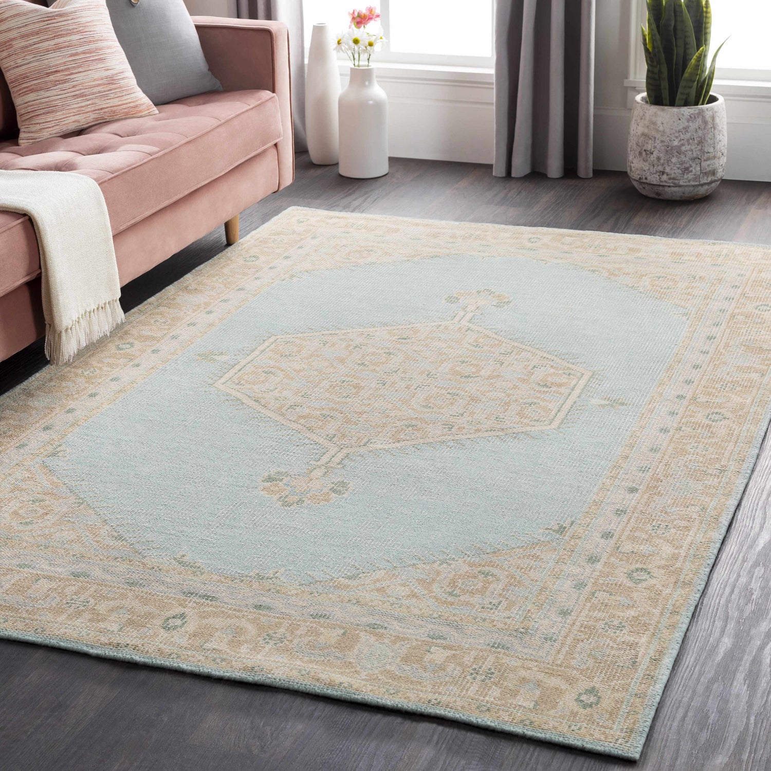 Living room scene with a Carpio Carpet in light sage and beige, pink sofa, and dark wood floors. Roomscene-Rectangle