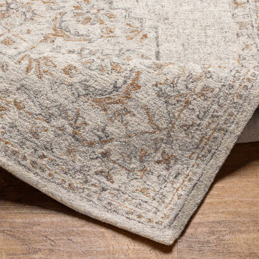 Close-up of the hand-tufted Currimao Area Carpet showing its neutral tones and traditional Persian-inspired pattern. Fold