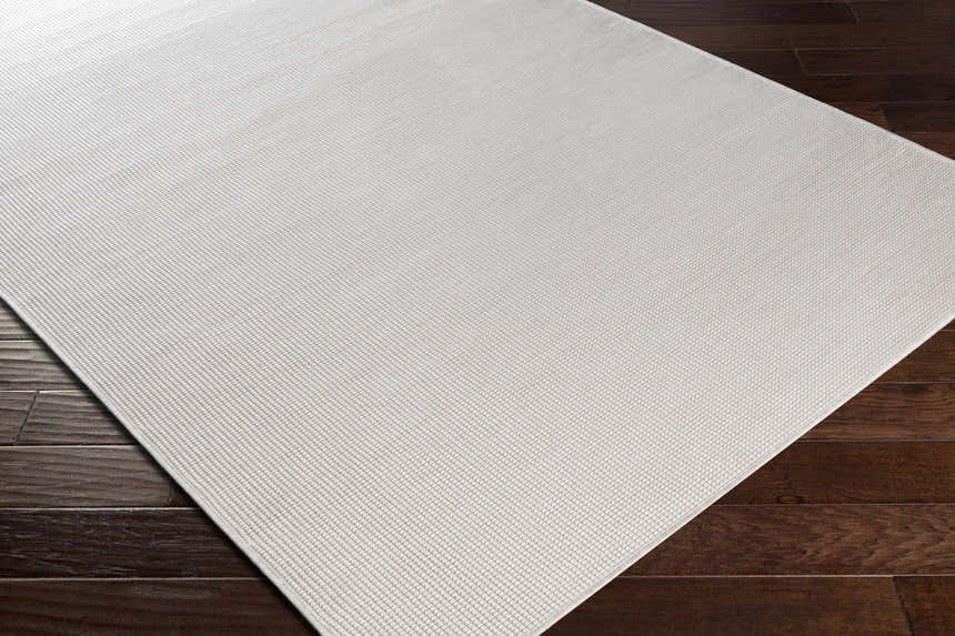 Close-up of cream Currimundi Area Rug showing woven texture and pattern on dark wood floor. Contemporary style. Corner