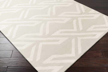 Close-up of the Castlederg Area Rug, ivory color with a geometric pattern on dark wood floors. Contemporary style. Corner