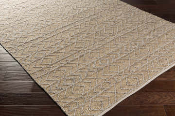 Close up of the hand woven Cullercoats Area Rug in camel and gray on dark wood flooring. Geometric pattern. Corner