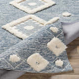 Close-up of the Curllsville Area Rug. Cream, wooly geometric shapes on a textured navy background. Hand-tufted rug. Fold