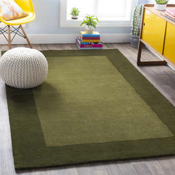 Living room scene with a Bordered Solid Olive Green Wool Rug, yellow chair, and modern cabinet. Roomscene-Rectangle