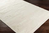 Close-up of the Cypress Cream Textured Wool Rug showing its woven design and soft, neutral color on dark wood floor. Corner