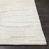 Close up of textured Cypress Cream Wool Rug on dark wood floor. Hand woven rug with natural fibers. Front