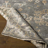 Close-up of the hand-knotted Dallas Area Rug. Charcoal, dusty sage, and tan oriental rug pattern. Viscose material. Fold