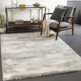 Living room scene with a gray chair and a soft, gray and white Dagami Area Rug. Roomscene-Rectangle