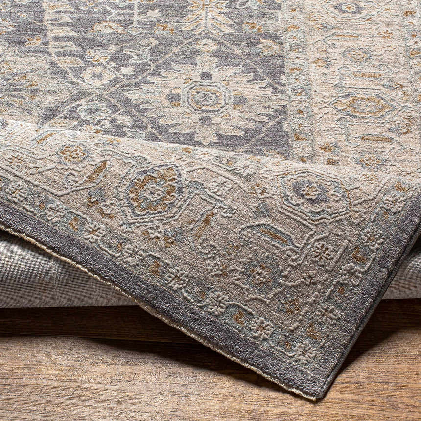 Close-up of the Dalupirip rug showing its traditional pattern, brown, denim, and gray colors, and thick, luxe texture. Fold