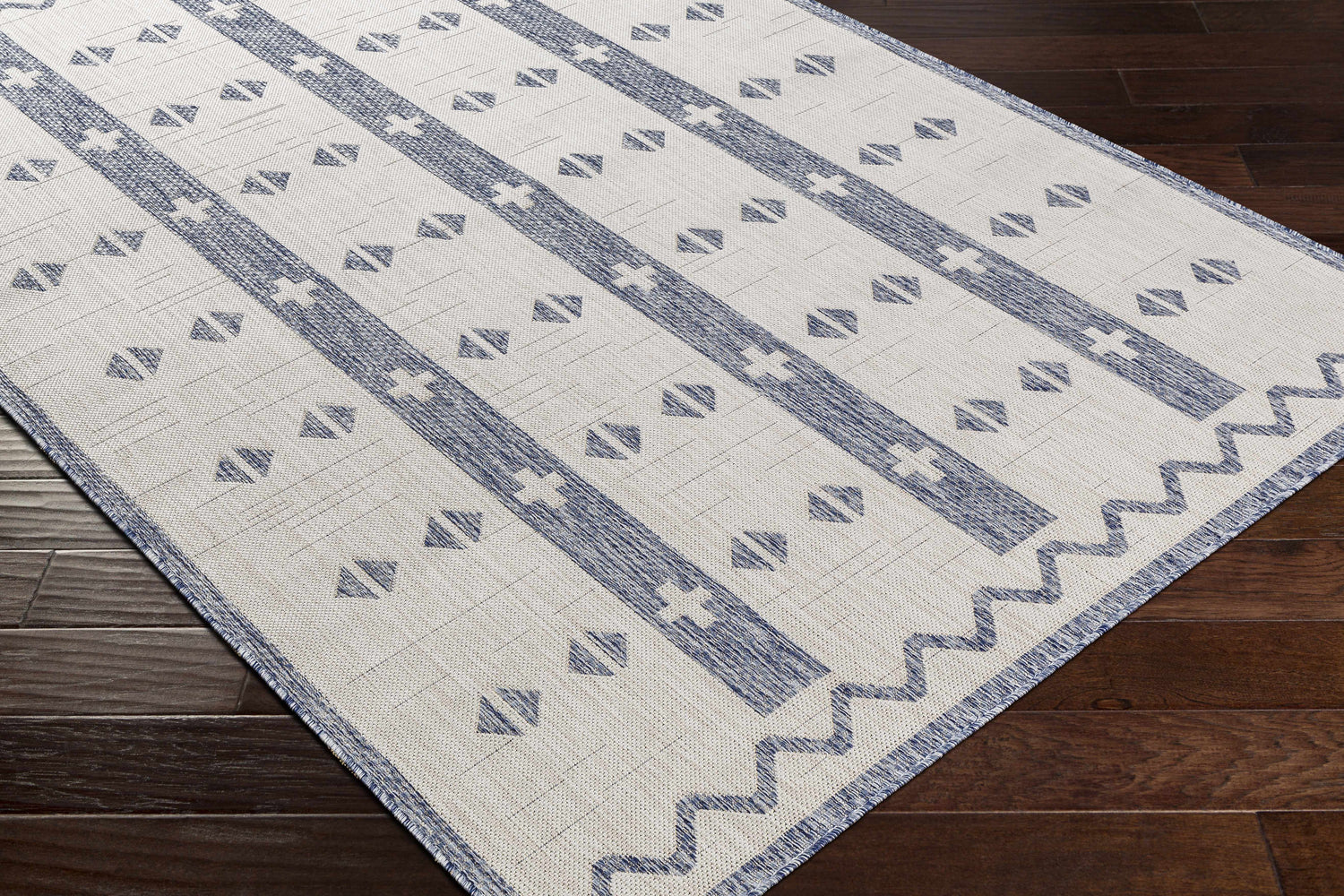 Close-up of Dapitan Indoor & Outdoor Rug. Dark gray and white rug with a contemporary geometric pattern. Corner
