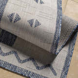 Close-up of the Dapitan Indoor & Outdoor Rug showing the woven texture and geometric denim and gray pattern. Fold