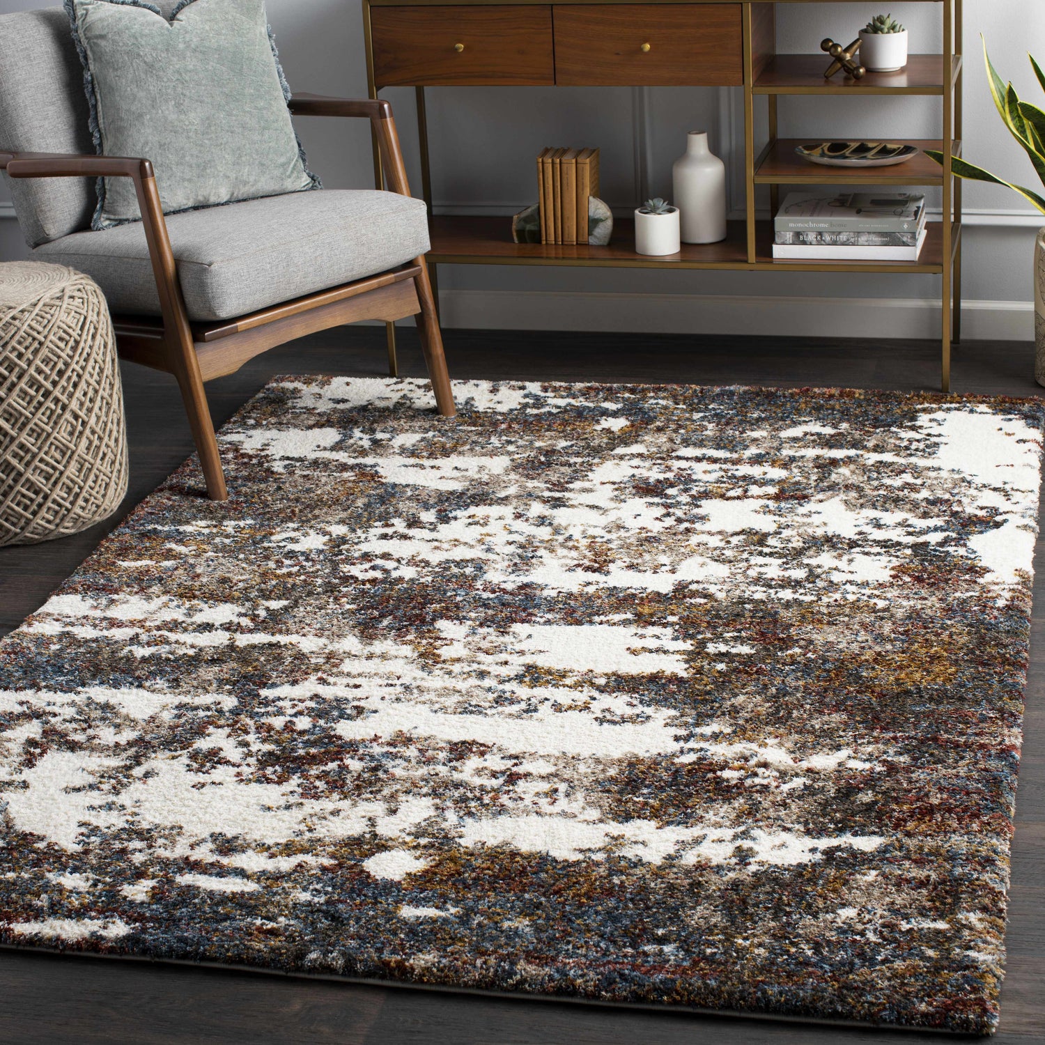 Living room scene with a contemporary Darenth Area Rug. Features a gray chair, wood console table, and a white, burgundy, and blue shag rug. Roomscene-Rectangle