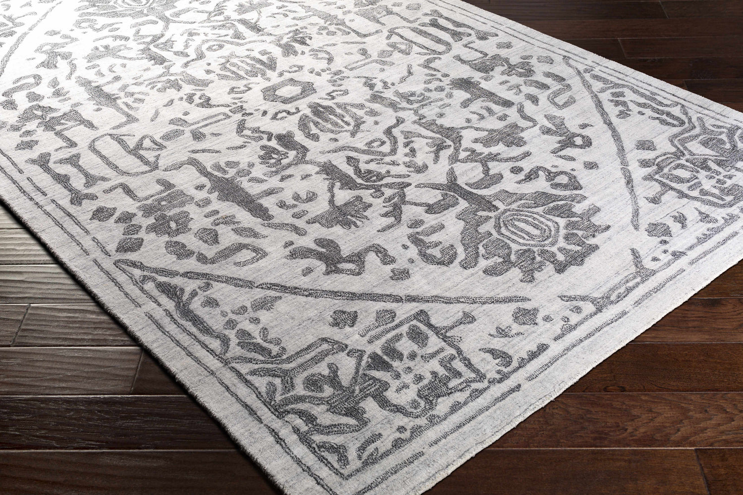 Close-up of the Darfield Area Rug, a hand-knotted viscose rug in black and light gray with a traditional, oriental-inspired pattern. Corner