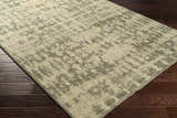 Close-up of the hand-knotted Davant Area Rug. Contemporary design in dusty sage, ivory and gray on dark wood floors. Corner