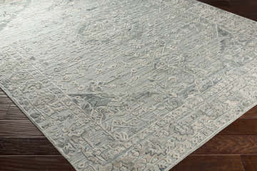 Close-up of the hand-loomed Davilla Area Rug. Light sage, seafoam, and light gray Persian-style pattern. Viscose texture. Corner