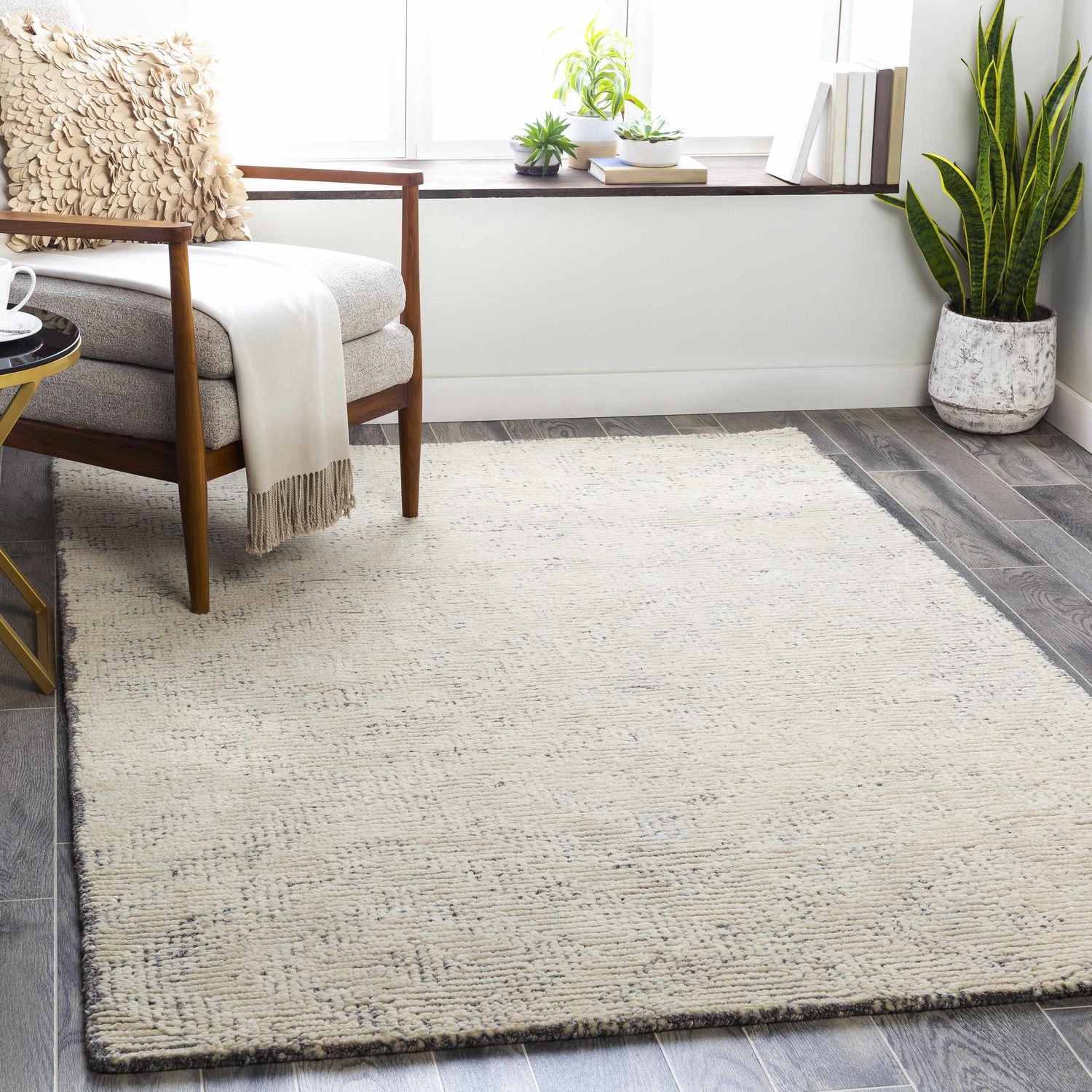 Living room scene with a cream Delahey Area Rug, wood chair, and natural light. Roomscene-Rectangle