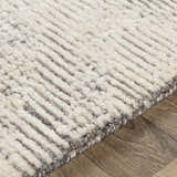 Close-up of the hand-tufted Delahey Area Rug. Cream and charcoal wool rug with a contemporary striped pattern and textured pile. Texture