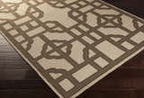 Close-up of the Desdemona Area Rug. Brown geometric pattern on a taupe, hand woven, 100% wool rug. Corner