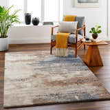 Living room scene with Deven Area Rug in camel, charcoal, and blue tones. Styled with a gray chair, wood side table, and potted plants. Roomscene-Rectangle
