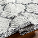 Close-up of the Dido Area Rug in charcoal and gray, showing hand-woven texture and geometric pattern. Fold