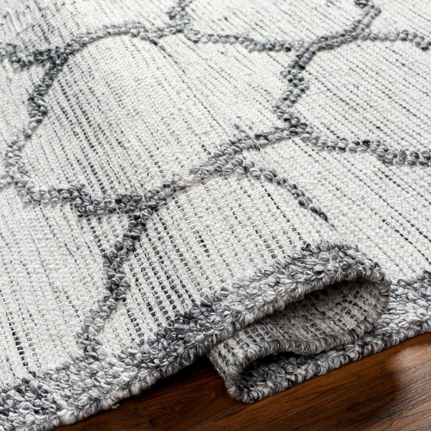Close-up of the Dido Area Rug in charcoal and gray, showing hand-woven texture and geometric pattern. Fold
