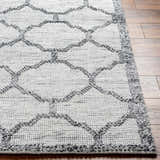 Close up of the hand woven Dido Area Rug, charcoal and gray geometric pattern on wood floor. Front