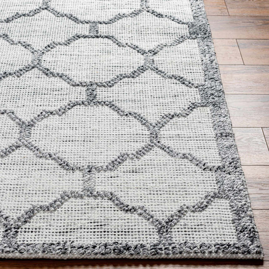 Close up of the hand woven Dido Area Rug, charcoal and gray geometric pattern on wood floor. Front