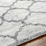 Close-up of the Dido Area Rug showcasing its charcoal and gray geometric pattern and hand-woven texture. Texture