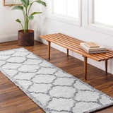 Entryway with a gray and charcoal Dido Area Rug, wood bench, potted plant, and hardwood floors. Roomscene-Runner