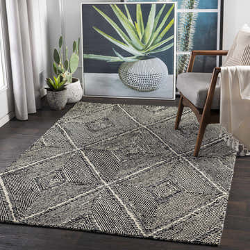 Living room scene with a black and cream Dimbulah Area Carpet, gray chair, and modern art. Roomscene-Rectangle