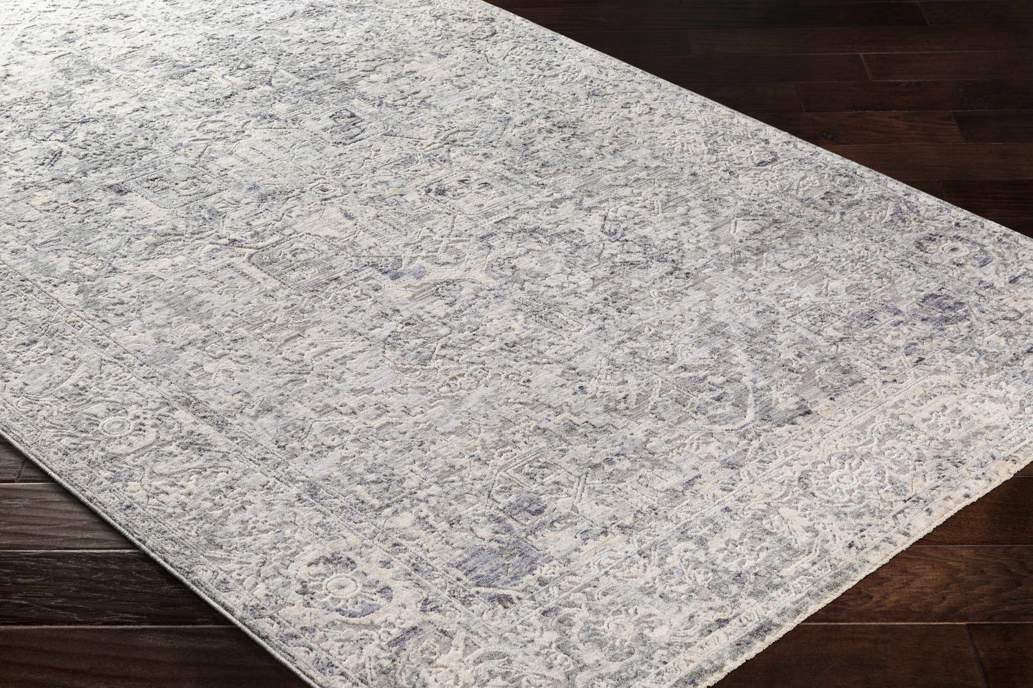 Close-up of the Dingwall Carved Statement Rug showing its traditional gray, ivory, and blue pattern and carved texture. Corner