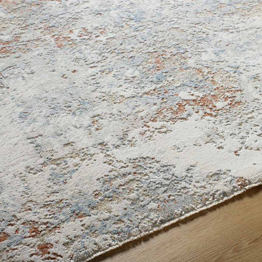 Close-up of the Dinos Thick Luxe Rug, showing its gray, nutmeg, and light blue abstract pattern and plush texture. Texture