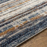 Close up of the Dumaguil rug showing a striped pattern in blue, brown, cream, and gray on a wood floor. Texture