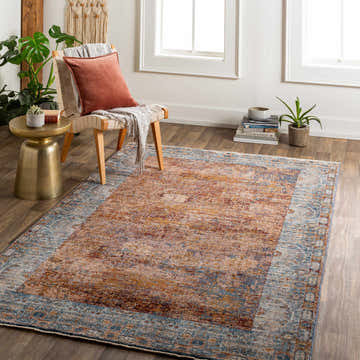 Bright room scene with a Demirci Area Rug in beige, burnt orange, and blue under a chair and side table. Roomscene-Rectangle